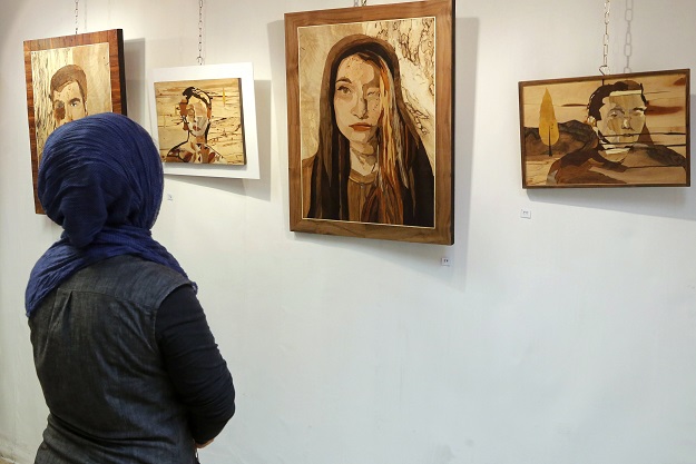 A woman looks at art work made by Iranian victims of acid attacks at the Ashianeh gallery in Tehran on February 28, 2018. Acid attacks have been an occasional scourge in Iran, with a spate of incidents in 2014 triggering protests and claims they were linked to women wearing 