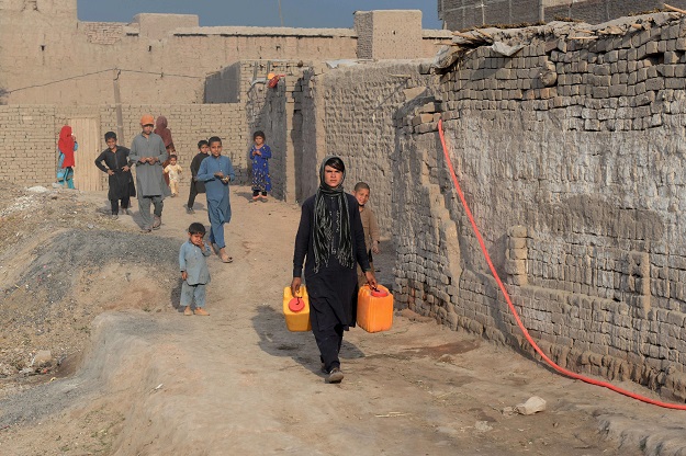 Afghan female labourer Sitara Wafadar, 18, who dresses as a male in order to support her family, collecting water near her home in Sultanpur village in Surkh Rod district, in Afghanistan's eastern Nangarhar province. PHOTO: AFP