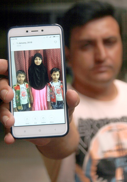 Siraj holds out his phone showing a picture of his children who are in India. PHOTO: ATHAR KHAN/ EXPRESS
