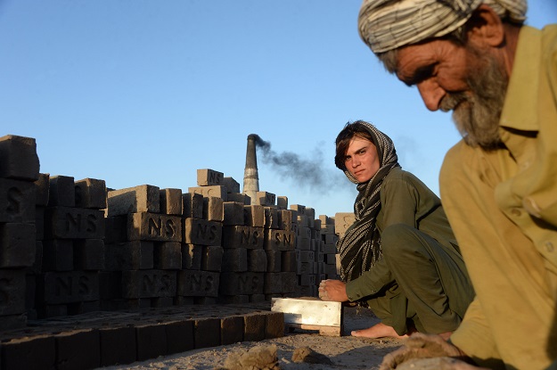 Afghan female labourer Sitara Wafadar, 18, who dresses as a male in order to support her family, working at a brick factory next to her elderly father (R) in Sultanpur village in Surkh Rod district, in Afghanistan's eastern Nangarhar province. PHOTO: AFP