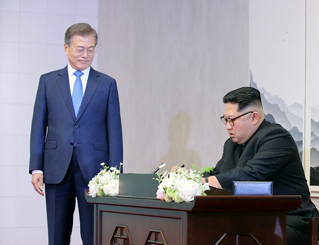  South Korean President Moon Jae-in watches as North Korean leader Kim Jong Un writes in a guestbook during their meeting at the Peace House at the truce village of Panmunjom inside the demilitarized zone separating the two Koreas, South Korea, April 27, 2018. PHOTO: REUTERS
