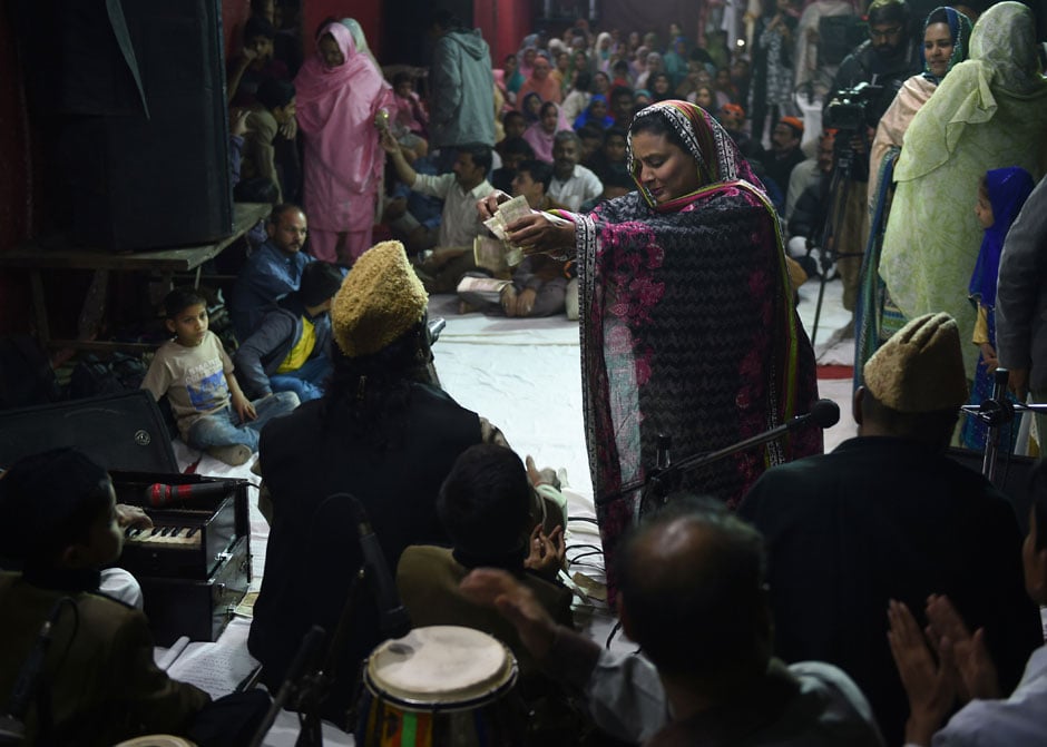 Qawwali singers Azmat Sabri (L) and his brother Talha Sabri (R) perform with their group as a devotee showers currency notes on them during an event in Karachi. PHOTO: AFP