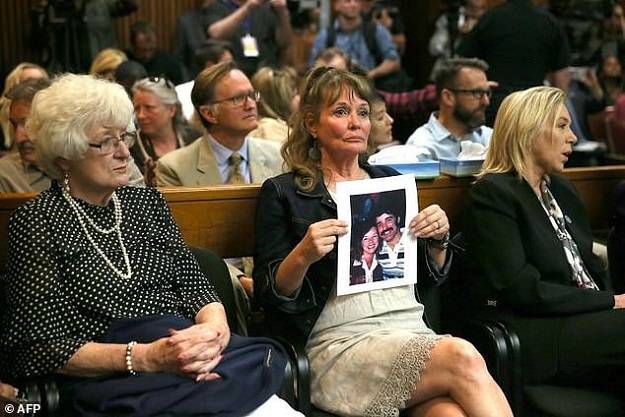 A woman holds a photo of Cheri Domingo and her boyfriend Gregory Sanchez, who were killed in 1981, at the arraignment of accused 'Golden State Killer' Joseph James DeAngelo. PHOTO: AFP