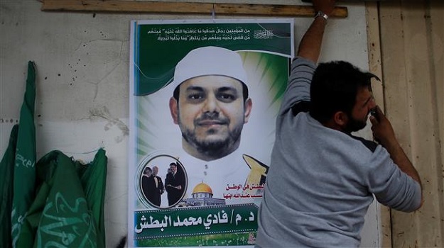 A man hangs a poster depicting Palestinian electrical engineer Fadi Mohammad al-Batash, who was shot dead in Malaysia, in his family house in the northern Gaza Strip on April 21, 2018. PHOTO: AFP