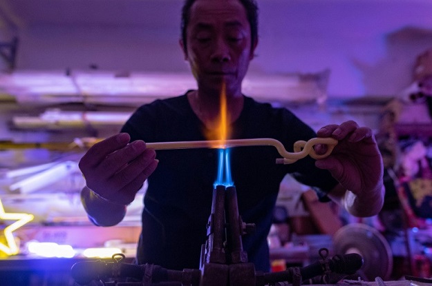 Wu Chi-kai bends glass tubes dusted inside with fluorescent powder into shape over a powerful gas burner. PHOTO: AFP