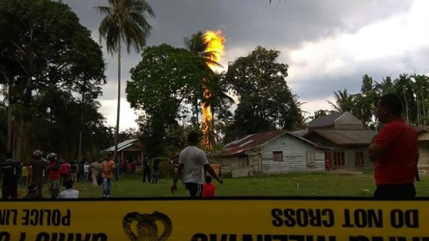 People watch as a fire burns at an oil well in Peureulak, Indonesia's Aceh province on April 25, 2018. PHOTO: AFP