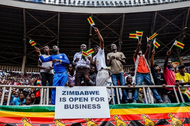 A placard reads 'Zimbabwe is open for business' as people cheer and dance during Zimbabwe Independence Day celebrations. PHOTO: AFP