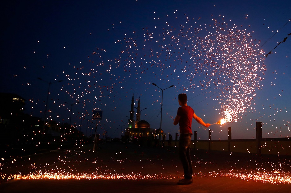 A Palestinian youth waves a sparkler next a mosque in Gaza City. PHOTO: AFP