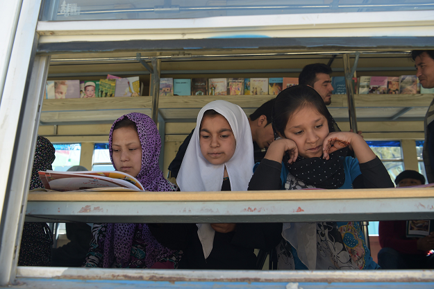 Afghan children read books in a mobile library bus in Kabul. The door of the blue bus slides open and dozens of children excitedly bound up the steps, eager to get their hands on hard-to-find books in Kabul's first mobile library. The library-on-wheels offers pupils and street kids free access to children's books, which are in short supply at public schools and libraries PHOTO: AFP