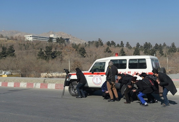 In this photo by slain AFP photographer Shah Marai, Afghan journalists take cover behind an ambulance near the Intercontinental Hotel during a fight between gunmen and security forces in Kabul on January 21, 2018. PHOTO: AFP