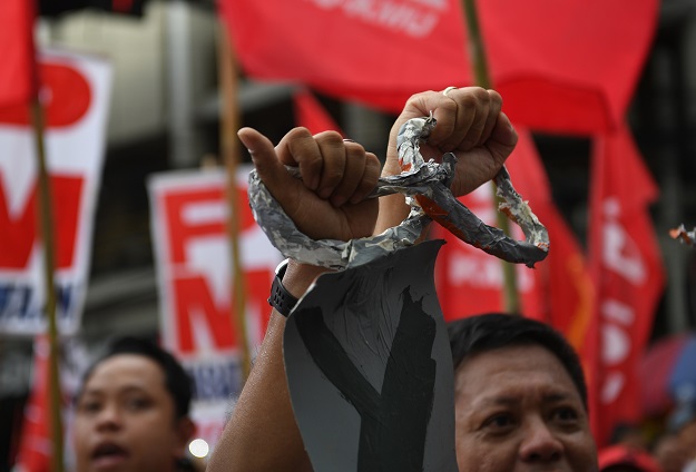 Activists along with workers break a mock chain during the May Day rally near Malacanang Palace PHOTO: AFP