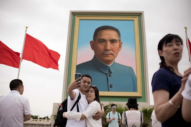 A couple takes a photo with a smartphone and selfie stick past a portrait of nationalist leader Sun Yat-sen in Tiananmen Square on the May Day holiday in Beijing. PHOTO: AFP