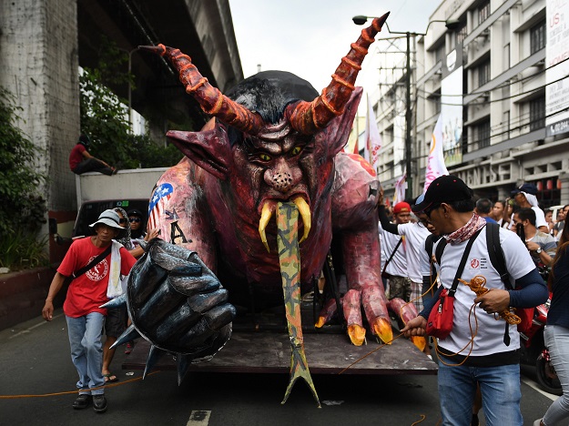 Activists pull a carriage loaded with a giant effigy of Philippine President Rodrigo Duterte as they march towards Malacanang palace during the May Day rally in Manila PHOTO: AFP