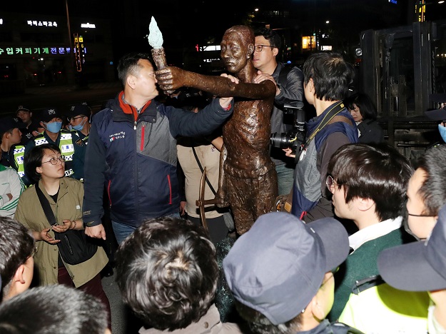 South Korean activists gather around a statue to former slave workers outside Japan's consulate in Busan late on April 30, 2018. Dozens of South Korean activists clashed with police May 1 as they tried to install a statue to former slave workers in front of one of Tokyo's consulates. South Korea and Japan are both democracies, market economies and US allies that face North Korea's nuclear threats and China's growing economic might, but ties between them are marred by historical issues PHOTO: AFP