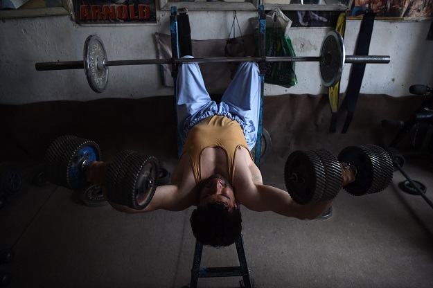 Afghan bodybuilder using dumbbells made from spare car parts as he exercises at the Aziz Aruzo bodybuilding gym in Kabul. PHOTO: AFP