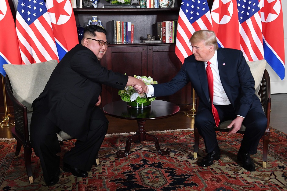 US President Donald Trump (R) shakes hands with North Korea's leader Kim Jong Un (L) as they sit down for their historic US-North Korea summit. PHOTO: AFP