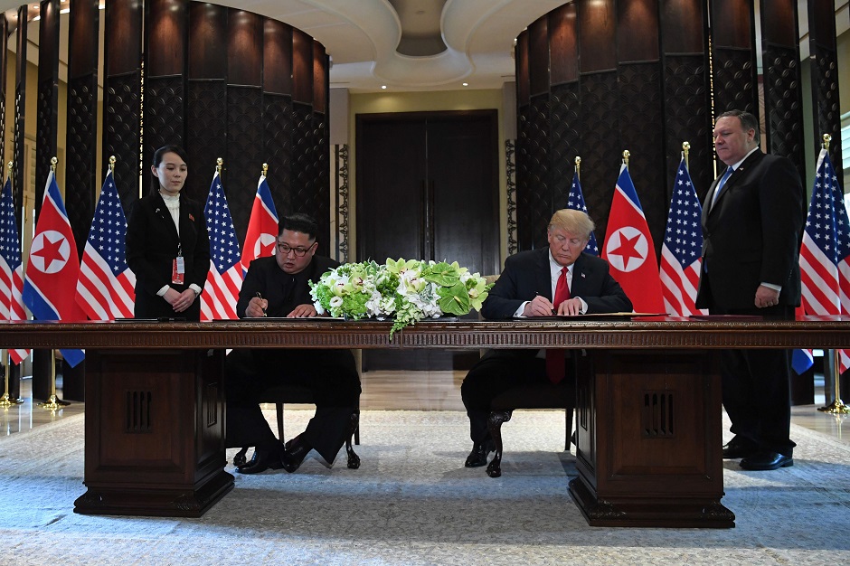 US President Donald Trump (2nd R) and North Korea's leader Kim Jong Un (2nd L) sign documents as US Secretary of State Mike Pompeo (R) and the North Korean leader's sister Kim Yo Jong (L) look on at a signing ceremony during their historic US-North Korea summit, at the Capella Hotel on Sentosa island in Singapore on June 12, 2018. PHOTO: AFP