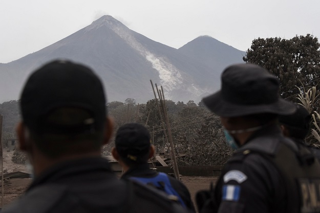 Police officers look at the Fuego Volcano from San Miguel Los Lotes, a village in Escuintla Department, about 35 km southwest of Guatemala City, on June 4, 2018, a day after an eruption. At least 25 people were killed, according to the National Coordinator for Disaster Reduction (Conred), when Guatemala's Fuego volcano erupted Sunday, belching ash and rock and forcing the airport to close PHOTO: AFP
