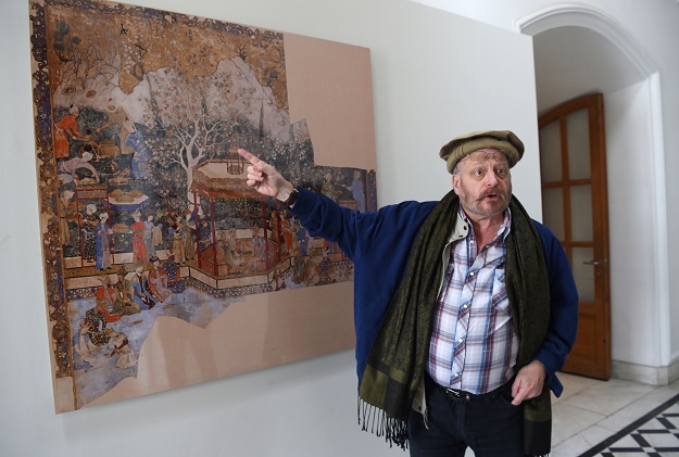 In this photograph taken on April 15, 2018, American historian Michael Barry gestures during an interview with AFP alongside artwork displayed at the 'King Babur's Kabul, Cradle of the Mughal Empire' exhibition at the Bagh-e-Babur Garden in the Afghan capital Kabul. Disfigured by four decades of war, the Afghan capital Kabul offers few reminders of its former glory in Islamic art or religious tolerance but a rare exhibition of Mughal paintings is seeking to change that PHOTO: AFP