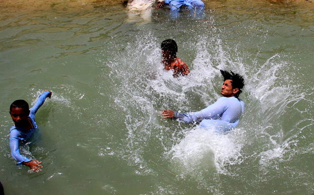 People bathing in a canal to cool off themselves. PHOTO: ATHAR KHAN