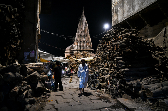 an indian man walking through the manikarnika ghat in the old quarters of varanasi photo afp