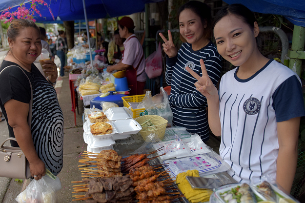 Thai vendors smile as they show victory signs near the hospital where the boys rescued. PHOTO:AFP