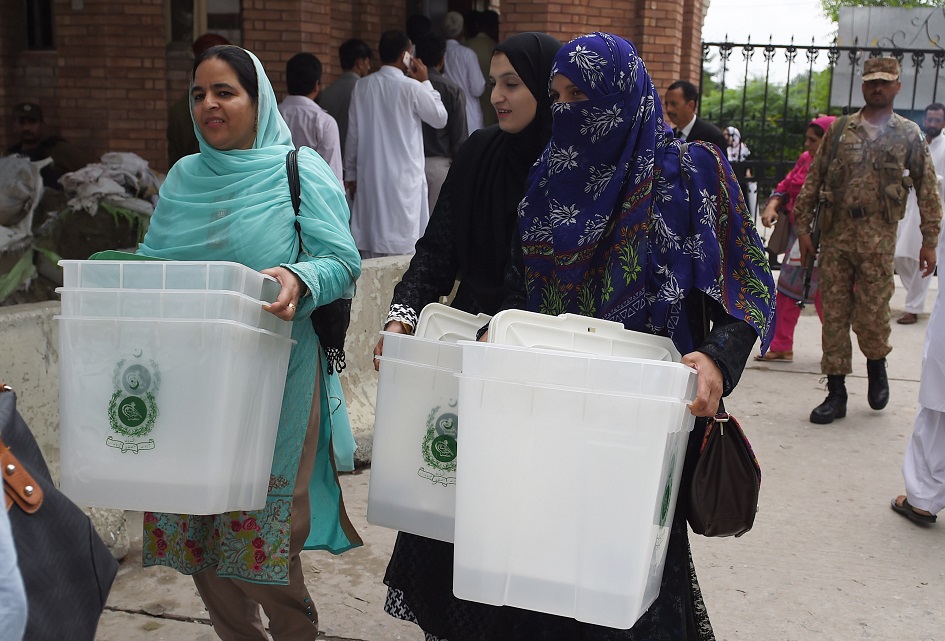 Presiding officers carry ballot boxes as they come out from the voting material distribution centre in Rawalpindi. PHOTO: AFP