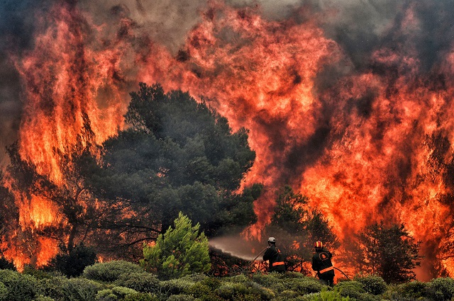 Firefighters try to extinguish flames during a wildfire at the village of Kineta, near Athens, on July 24, 2018. Raging wildfires killed 74 people including small children in Greece. PHOTO: AFP