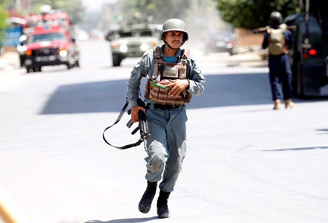An Afghan policeman runs at an area where explosions and gunshots were heard. PHOTO: REUTERS