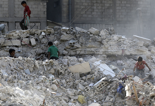  Children play amid the rubble of destroyed buildings in Harasta. PHOTO: AFP.