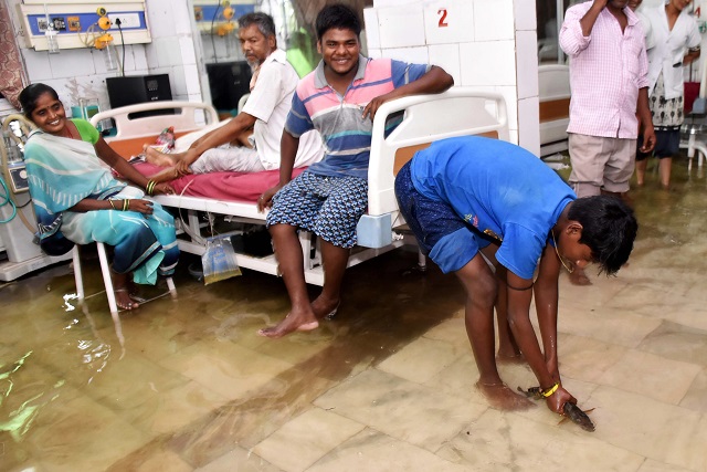 This photograph taken in July 29 shows a relative's patient holding a fish after he caught it inside a waterlogged hospital ward. PHOTO: AFP