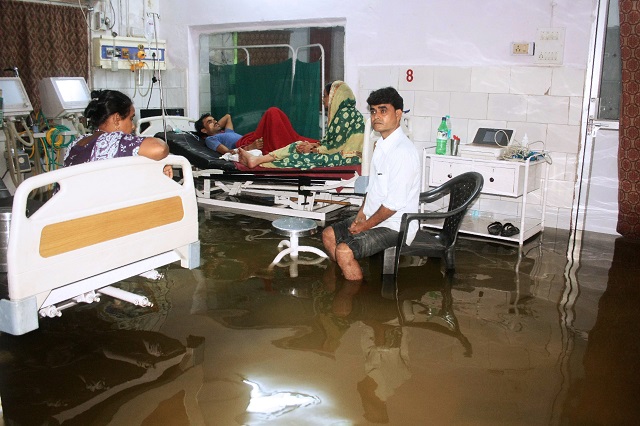 This photograph taken in July 29 shows a patient and relative sitting in a hospital beds inside a waterlogged room. PHOTO: AFP