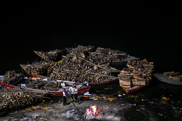 Indian men waiting for a dead body to finish being cremated at the Manikarnika ghat. PHOTO: AFP.