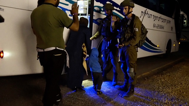 This handout video grab from the Israeli army released on July 22, 2017, shows Israeli soldiers guiding members of families of Syrian White Helmet rescuers into a bus. PHOTO: AFP
