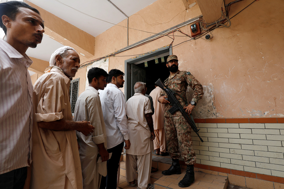 People line up at a polling station during the general election in Karachi. PHOTO: REUTERS.