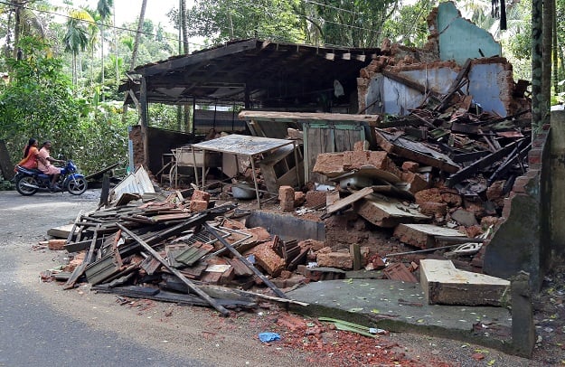 People ride a motorbike past the rubble of a small restaurant which collapsed due to floods in Paravur in the southern state of Kerala, India. PHOTO: REUTERS