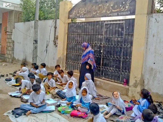 Students of Ali Muhammad Iqbal Government School in Gulshan-e-Iqbal had to take classes on the road outside the school after it was found locked in the morning. PHOTO: INP