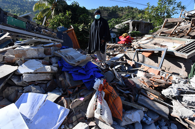 A woman walks through rubble of damaged houses in Menggala. PHOTO:AFP