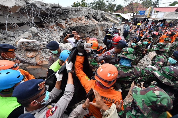 Members of a search and rescue team carry the body of a quake victim found amongst the rubble in Bangsal. PHOTO:AFP
