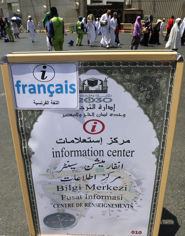 Muslim pilgrims walk past an information of the poster of the translation bureau in the Saudi holy city of Mecca. PHOTO:AFP