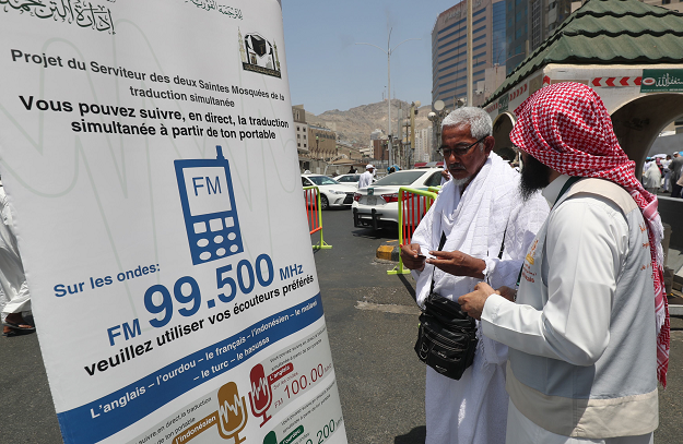 A translator helps pilgrims find information on a poster displaying helpful smartphone applications in the Saudi holy city of Mecca, ahead of the start of the Hajj pilgrimage. PHOTO:AFP
