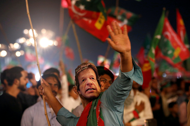 A supporter of Imran Khan, chairman of the Pakistan Tehreek-e-Insaf (PTI), political party, wears a mask and dance on party songs during a campaign rally ahead of general elections PHOTO:REUTERS
