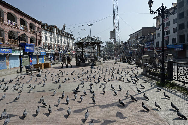 Indian paramilitary troopers patrol past pigeons during the first day of a strike . PHOTO:AFP
