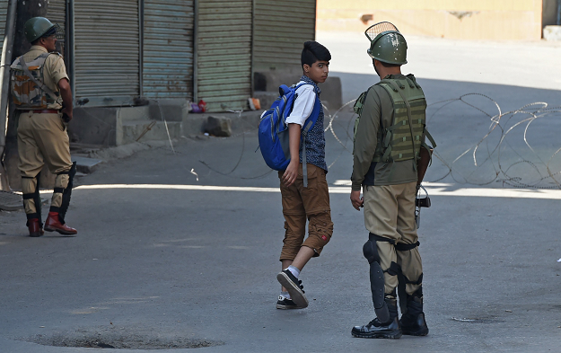 Indian paramilitary troopers question a Kashmiri boy during the first day of a strike. PHOTO:AFP