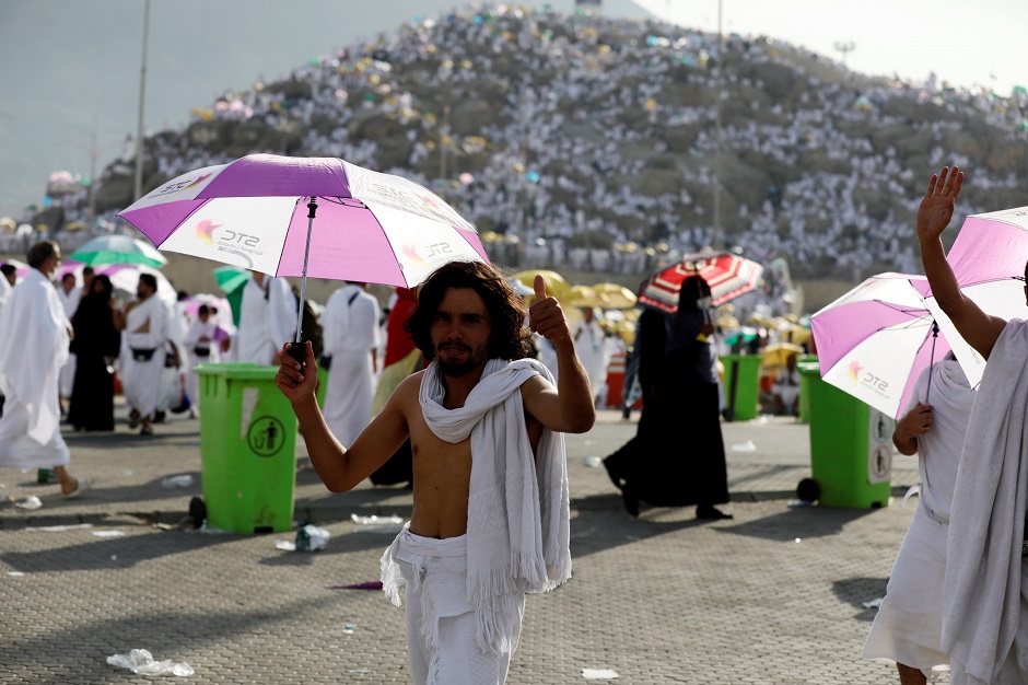 A pilgrim from Syria gestures as others gather on Mount Arafat in the background during Hajj on August 20, 2018. PHOTO:REUTERS