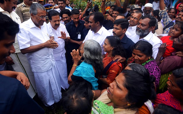 Kerala chief minister Pinarayi Vijayan (L) along with opposition leader Ramesh Chennithala (2L) visit relief camp in Chengamanadu. PHOTO: AFP