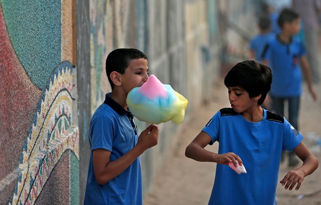 Pupils eay candy floss in front of a school run by the United Nations Agency for Palestinian Refugees (UNRWA) in Gaza City on August 29, 2018. PHOTO: AFP