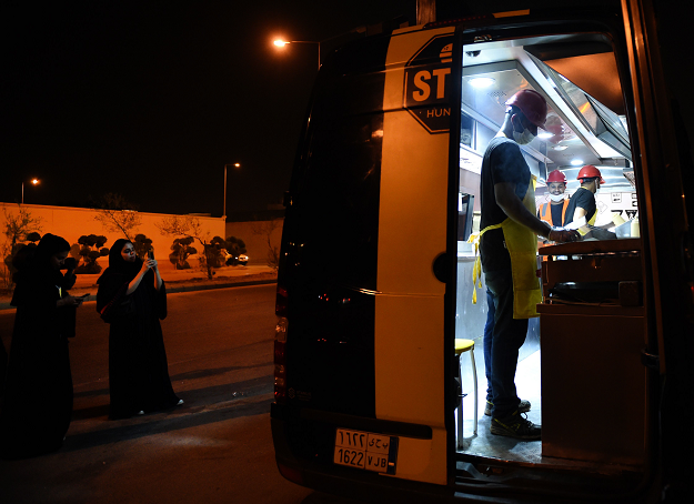 Saudi women filming the food truck One Way Burger while waiting for their order at a main street in the capital Riyadh. PHOTO: AFP