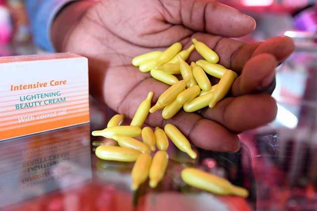 A beautician displays capsules and cream used for skin lightening at a beauty shop, in Nairobi on July 6, 2018. - Africa is experiencing a massive trend of skin bleaching. PHOTO: AFP
