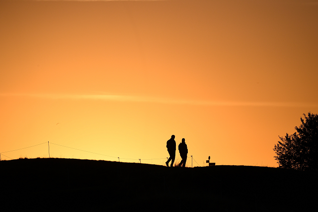 men walk on a fairway at sunrise ahead of the 42nd ryder cup at le golf national course in france photo afp